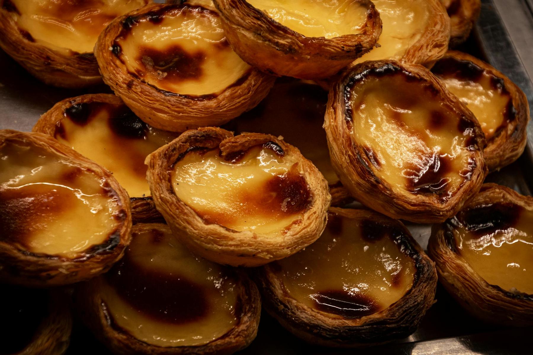 A close-up view of several Portuguese custard tarts, also known as pastéis de nata, with flaky crusts and caramelized tops.